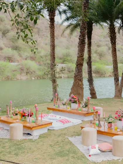 Low-seating 'baithak' arrangements by the lake for a relaxed 'gupshup' session during the Mehendi.