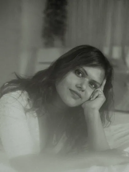 An intimate indoor portrait in black and white. The model's soft smile and relaxed pose, combined with a dreamy, foggy effect, result in a gentle and timeless image.