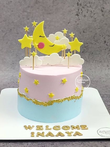 A "Welcome Inaaya" cake with a moon and stars theme. The pink and blue dual-tone design is perfect for welcoming a new baby girl.