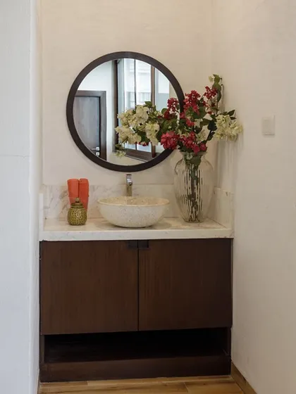 The bathroom for the private gym space. We kept it simple and elegant with a dark wood vanity, a stone vessel sink, and a large round mirror to complement the home's overall aesthetic.