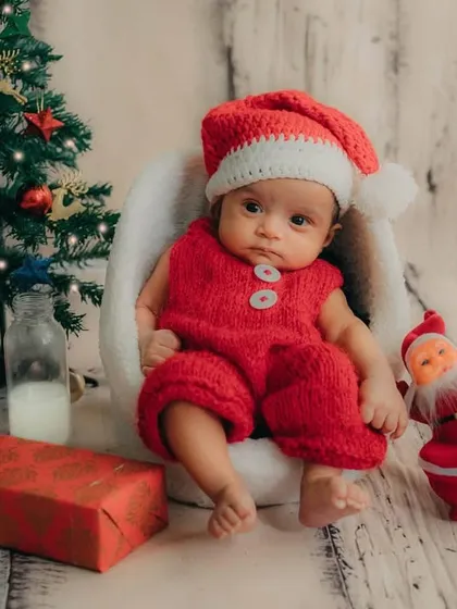 Posing with a tiny Santa and reindeer, this 2-month-old is all set for his first Christmas celebration.