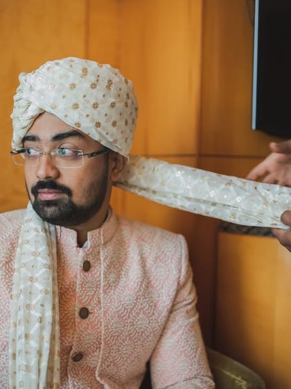 The groom gets help with his 'safa' tying. A classic getting ready shot that focuses on tradition and camaraderie.