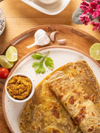 A top-down shot of a meal featuring parathas and a bowl of Peppal's chutney. This shows the product in a real-life serving suggestion, making it more relatable.