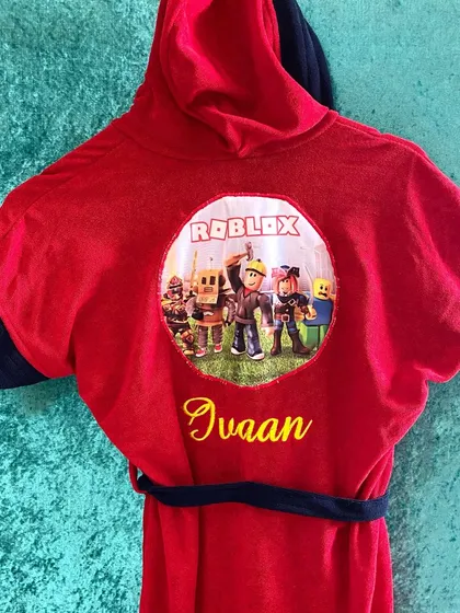 This red Roblox themed bathrobe is perfect for young gamers. It's personalised with the name 'Ivaan' and is made from soft, absorbent towel material.