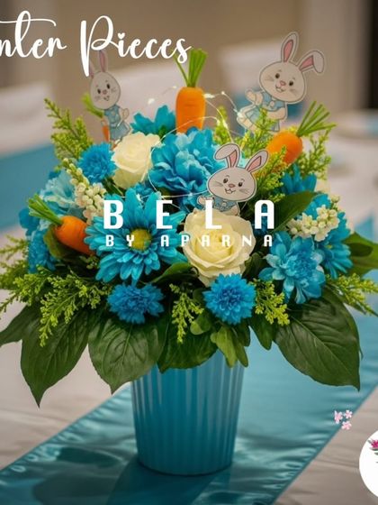 A floral centerpiece featuring bright blue and white flowers in a matching vase. The arrangement is accented with small rabbit and carrot cutouts, adding a whimsical touch to the guest tables.