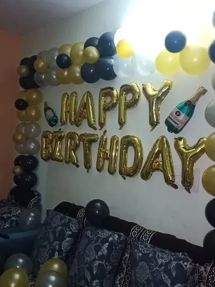A simple wall decoration for a home birthday party, using gold foil 'Happy Birthday' letters and a black and gold balloon garland.