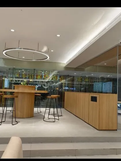 A modern lounge and discussion area within a retail showroom, featuring a mix of wood, glass, and metal. We design these spaces to be both functional and aesthetically pleasing, enhancing the overall customer journey.