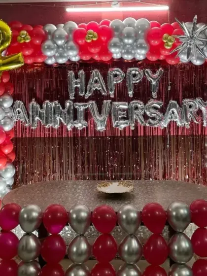 This rectangular backdrop combines a metallic shimmer curtain with a full balloon frame in red, silver, and chrome. The "Happy Anniversary" foil letters make it a complete and festive setup for a lively party at home.