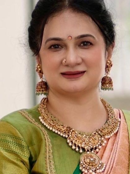 A close-up portrait of Vani Reddy. Her grace is accentuated by the soft colors of the saree and her traditional jewelry.