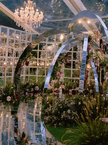 We dreamt up this one-of-a-kind contemporary mandap for Nidhi and Amit, featuring mirrored arches that reflected the lush floral gardens we created inside a clear marquee. It was a modern fairytale, built to reflect their unique personalities, even amidst a cyclone in Bangalore.