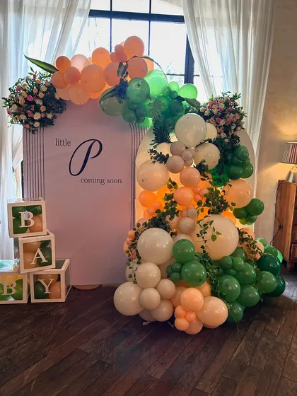 The main backdrop for the tropical baby shower, with 'Little P coming soon' signage, wooden baby blocks, and a lush arrangement of balloons and florals.