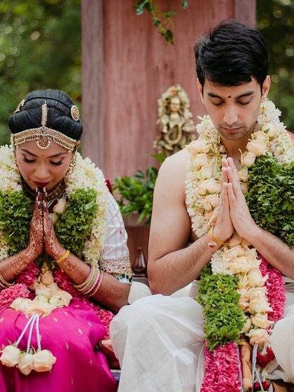 The couple in a moment of prayer during their ceremony, their hands joined in reverence.