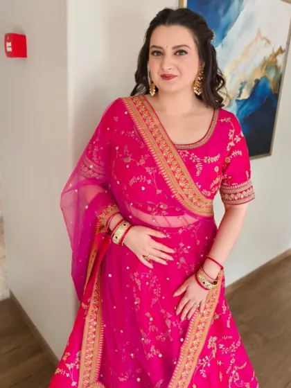 A beautiful, radiant look for a wedding reception. The makeup is soft and glowing, paired with romantic curls and a stunning pink lehenga for a festive and elegant appearance.