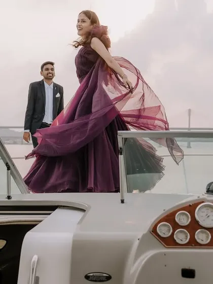 A glamorous pre-wedding shoot on a yacht in Goa. The wind catching her flowing gown against the open sea creates a dramatic, high-fashion image that feels both powerful and romantic.