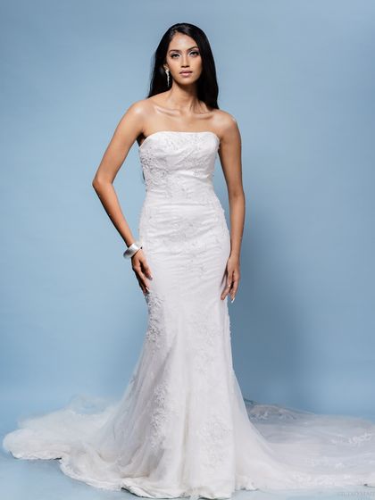 A stunning full-length shot of a model in an elegant white, strapless bridal gown against a soft blue background. This highlights my work in editorial bridal fashion.