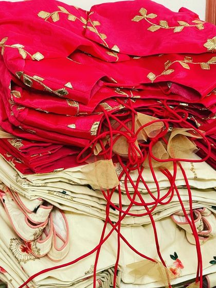 Stacks of finished blouses, ready to be sent to their new homes. These pieces, in vibrant pink and elegant cream, showcase our detailed embroidery and finishing.
