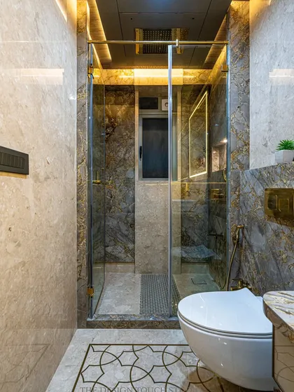 A view of the glass-enclosed shower area, which helps to create a clear separation between wet and dry zones. The golden fixtures add a touch of sophistication.