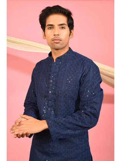 This portrait shot highlights the intricate chikankari and sequin detailing on the front of the navy blue kurta. It is a classic piece designed for understated elegance during the festive season.