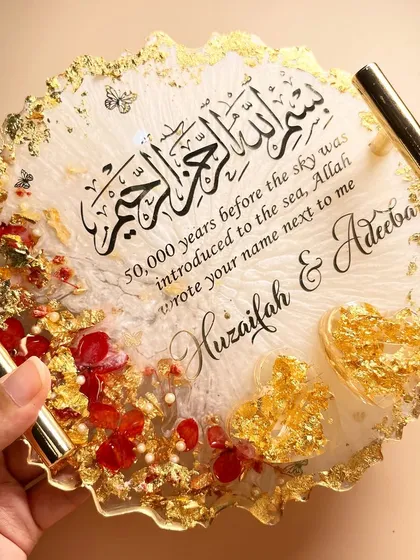 A hand holding the red and gold ring tray to show its size and glossy finish.