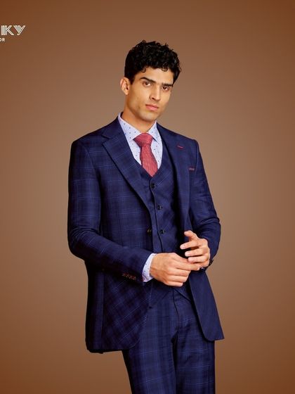 This navy blue plaid three-piece suit is a statement of timeless elegance. Paired with a contrasting red tie, it is perfect for making a flawless impression at any memorable occasion.