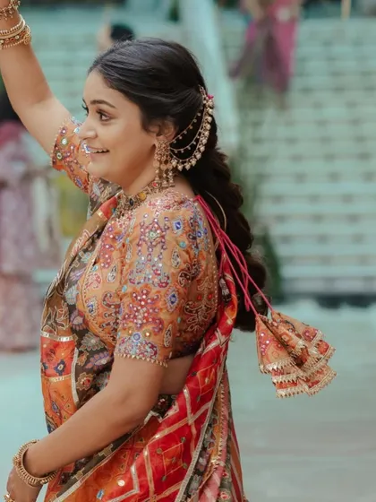 A side view of the pooja hairstyle, showing the beautiful hair accessory and the tassel detail.