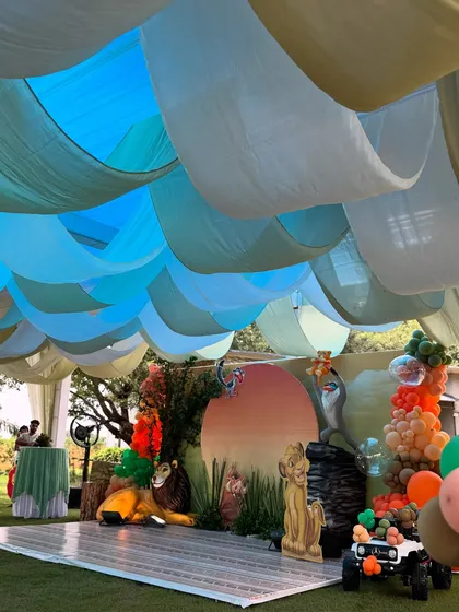 The ceiling of the party tent was draped with flowing blue and white fabric to create the feeling of being under a vast African sky. This detail adds to the immersive quality of the event.