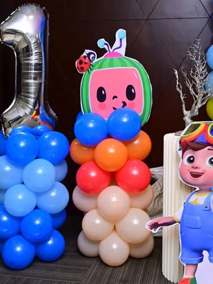 A close-up of the Cocomelon balloon pillars and character standees I created for a first birthday party at Savoury Restaurant in Madiwala.