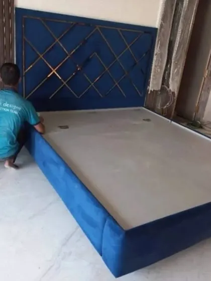 My team member is making final adjustments to this royal blue upholstered bed. The headboard features a geometric pattern created with metal inlays, a popular choice for modern luxury bedrooms.