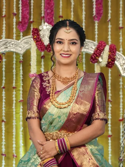 A smiling portrait of Harshitha at the naming ceremony. Her makeup is fresh and enhances her natural glow.