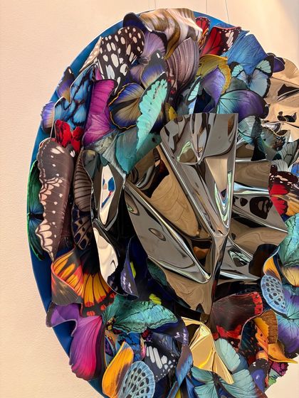 A close-up of the crumpled metallic center of "Metamorphosis in Metal," reflecting the surrounding butterfly wings.