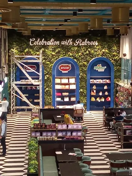 A massive artificial green wall provides a stunning backdrop for the "Celebration with Rabrees" display, adding a touch of nature to the commercial interior.