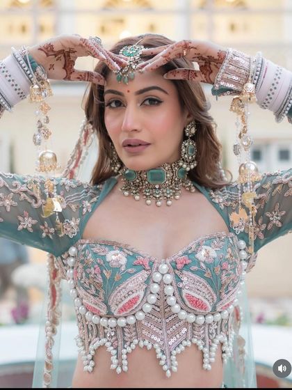 A close-up of the exclusive designer pastel green lehenga. The corset blouse with pearl detailing is a high-fashion element that makes this piece truly special.