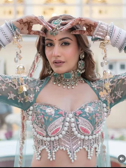 A close-up of the exclusive designer pastel green lehenga. The corset blouse with pearl detailing is a high-fashion element that makes this piece truly special.