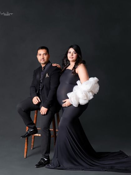 A sophisticated maternity portrait with the couple seated, dressed in elegant black. This style is timeless and powerful.