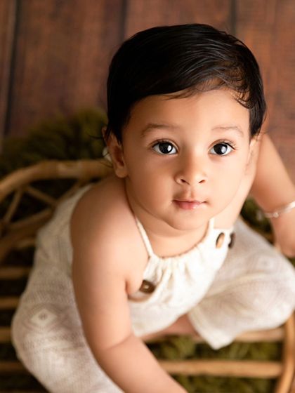 A high-angle shot of a baby boy looking up from a wicker basket, creating an engaging and direct portrait.