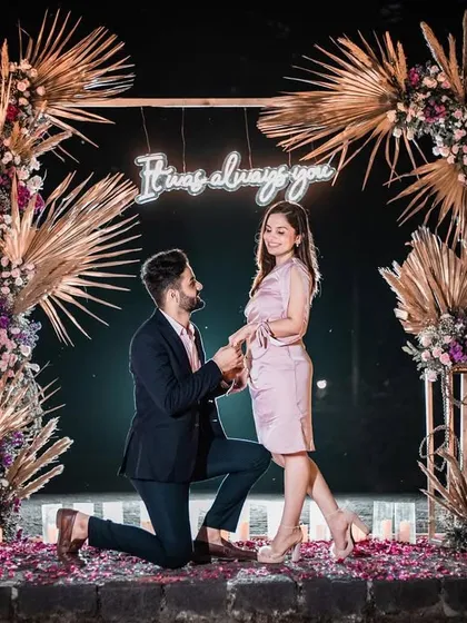 The perfect moment. We create the backdrop for your forever story, like this romantic boho-chic proposal setup complete with a custom neon sign, pampas grass, and the warm glow of countless candles.