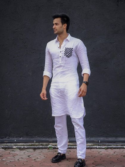 A modern twist on a classic. This crisp white linen kurta features a bold, checkered pattern on the pocket, offering a unique and stylish statement.