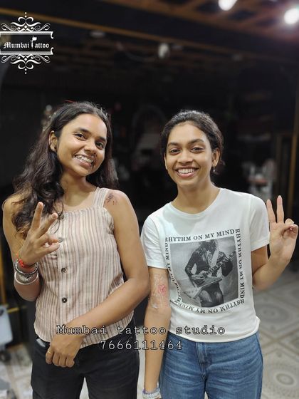 Two happy friends posing after their tattoo session. We strive to make our studio a welcoming place where friends can share a memorable experience.