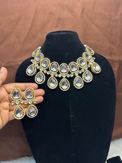 This simple yet elegant choker set is perfect for a minimalist look or for guests. It features large, clear Kundan-style stones with matching earrings. It's a high-quality, versatile piece available for rent.