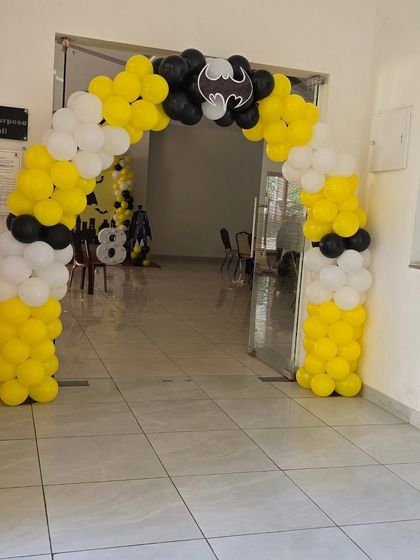 A Batman themed balloon arch at the entrance to a multipurpose hall, setting the tone for the party.
