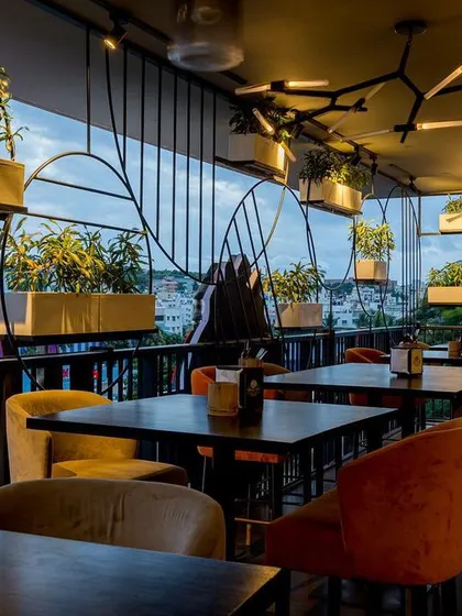 A wider view of the balcony dining area, where the decorative safety grill becomes a key part of the design. The hanging planters add a layer of green, enhancing the connection to the outdoors.