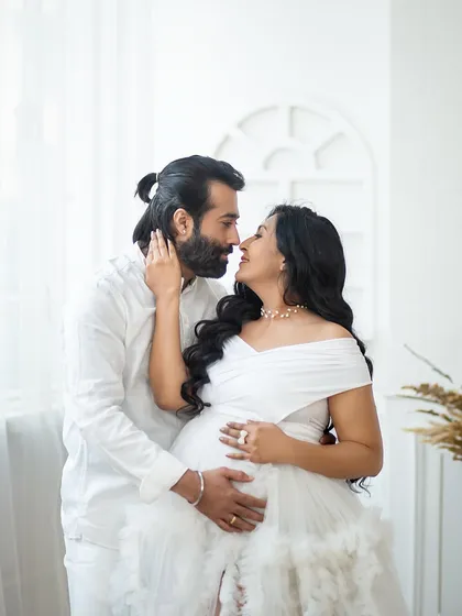 An intimate and romantic close-up. The all-white theme and soft lighting enhance the feeling of tenderness and connection.