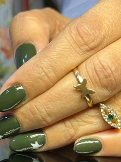 A chic olive green manicure with small white star accents for a subtle, military-inspired look.