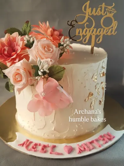 A simple yet elegant "Just Engaged" cake with a cascade of beautiful sugar flowers and delicate gold leaf accents.
