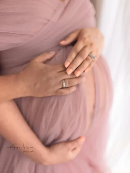 A close-up on the hands cradling the bump, a simple yet powerful gesture of love and protection. This shot captures the details and the deep connection of this special time.