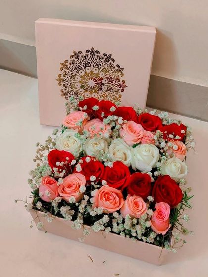 An elegant square box overflowing with a mix of red, pink, and white roses, accented with baby's breath. This sophisticated arrangement is perfect for any celebration, from Rakhi to anniversaries.