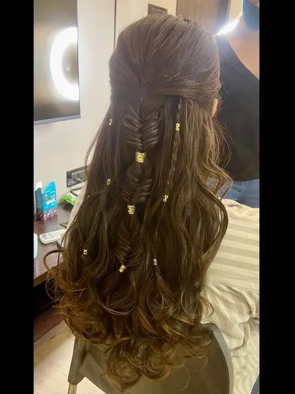 A boho-inspired half-updo with a fishtail braid and beachy waves, accented with gold hair charms.