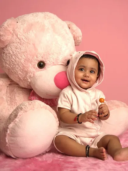 A sweet baby poses with a giant pink teddy bear in our studio. This is the "before" shot for one of our AI transformations.