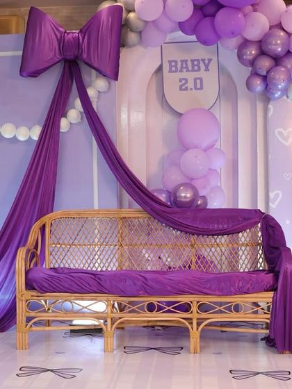The elegant rattan bench draped in purple fabric, ready for the parents-to-be. This seating was a beautiful focal point for the bow-themed stage.