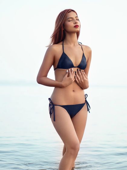 A serene and beautiful portrait of a model in a bikini, standing in the water. The focus is on her calm expression and the peacefulness of the ocean.